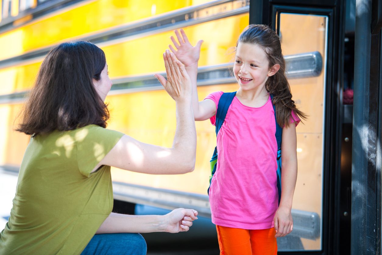 counselor high-fiving student before getting on bus